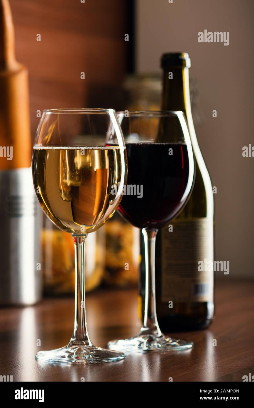 Französischer weiß- und Rotwein in Gläsern mit Blasen auf dem Tisch eine Küche mit einer Weinflasche im Hintergrund Stockfoto