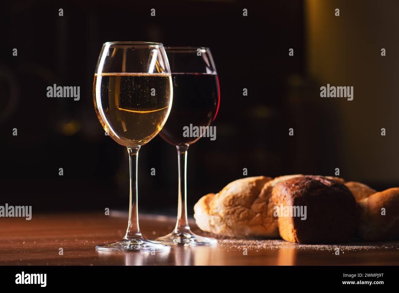 Französischer weiß- und Rotwein in Gläsern mit Blasen auf dem Tisch mit Brot in dunklem Hintergrund, Nahaufnahme Stockfoto