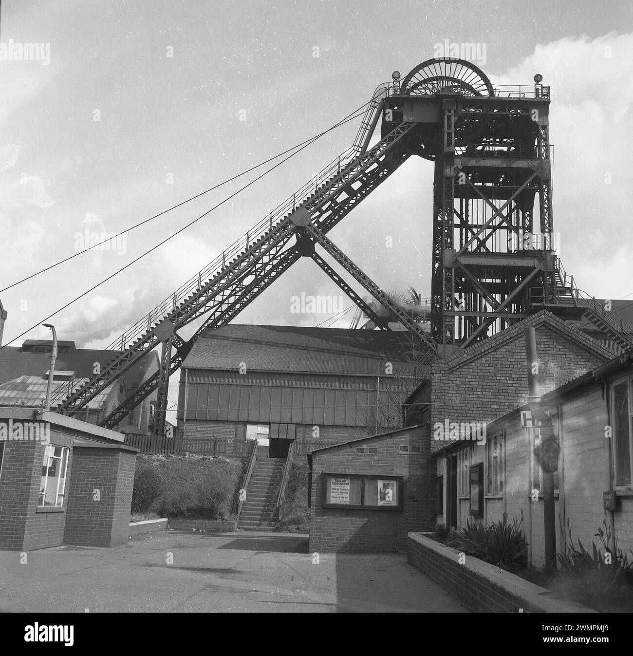 1973, historisch, Außenseite eines Grubenschachts, mit dem oberirdischen Stahlrahmen oder dem Wendeturm, Sheffield, England, Vereinigtes Königreich. Auf einem Poster im Fenster des Bergbaubüros steht: Erste-Hilfe-Wettbewerbe, Doncaster Area, Junior- und Senior-Finals an der Don Valley High School in Sheffield. Stockfoto