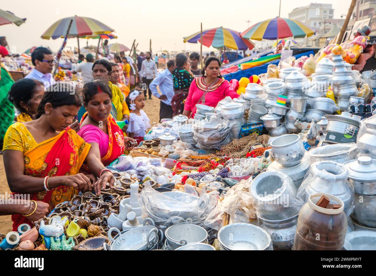 Indische Frauen drängen sich an einem Verkaufsstand, der Kochgeschirr am Strand von Puri, Indien, verkauft Stockfoto