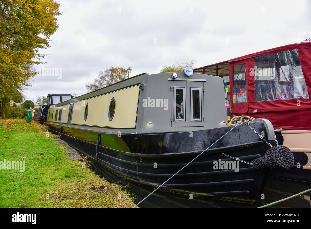 Schmalboot auf einem Anlegeplatz auf einem Kanal auf den Binnenwasserstraßen Großbritanniens. Stockfoto