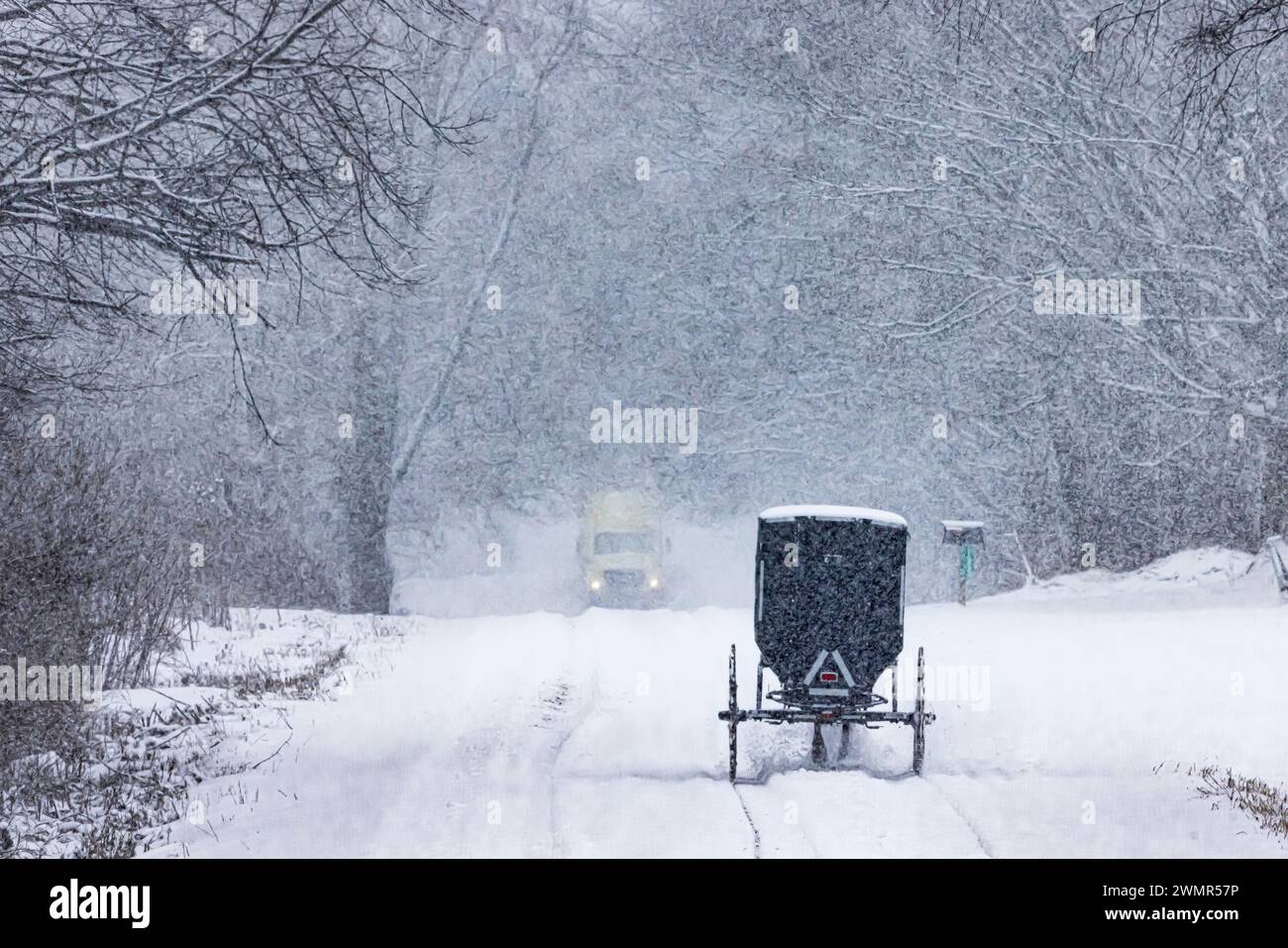 Amish-Buggy und Lieferwagen auf der Landstraße während eines Schneesturms im Mecosta County, Michigan, USA Stockfoto