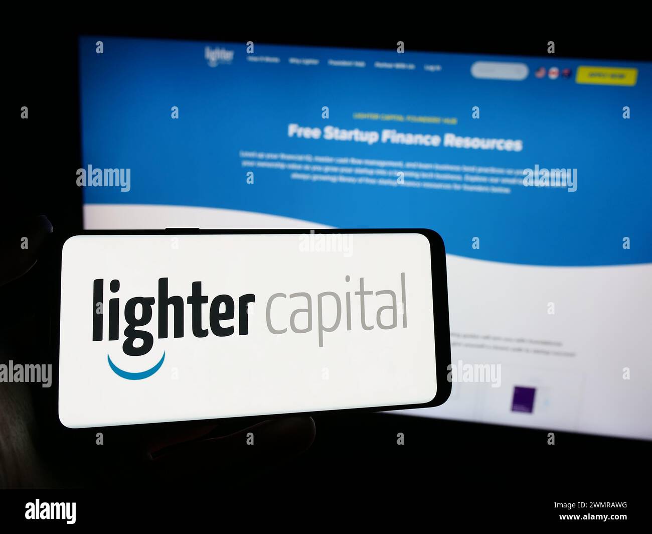 Person, die ein Mobiltelefon mit dem Logo des amerikanischen Finanzierungsdienstleisters Lighter Capital Inc. Vor der Webseite hält. Schwerpunkt auf dem Display des Telefons. Stockfoto