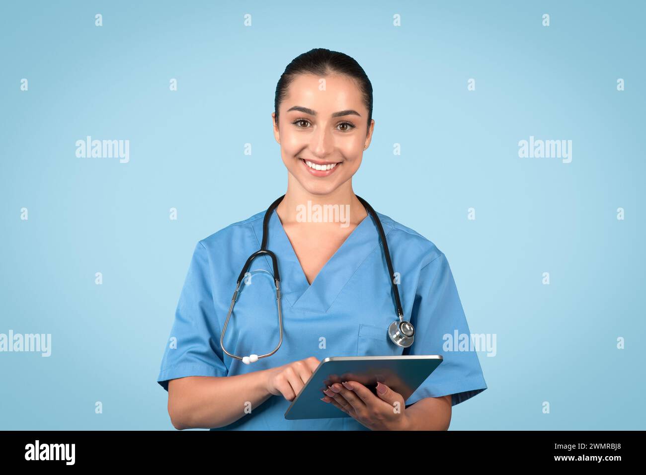 Aufmerksame Krankenschwester in Peelings mit Tablet lächelnd in die Kamera Stockfoto