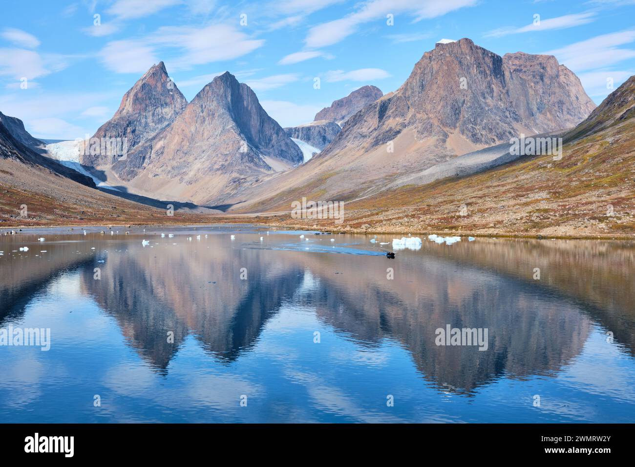 Spitze Gipfel und Gletscher der Dronning Marie Dal spiegeln sich in ruhigen Gewässern des Fjords in der Nähe von Skoldungen, Ostgrönland Stockfoto