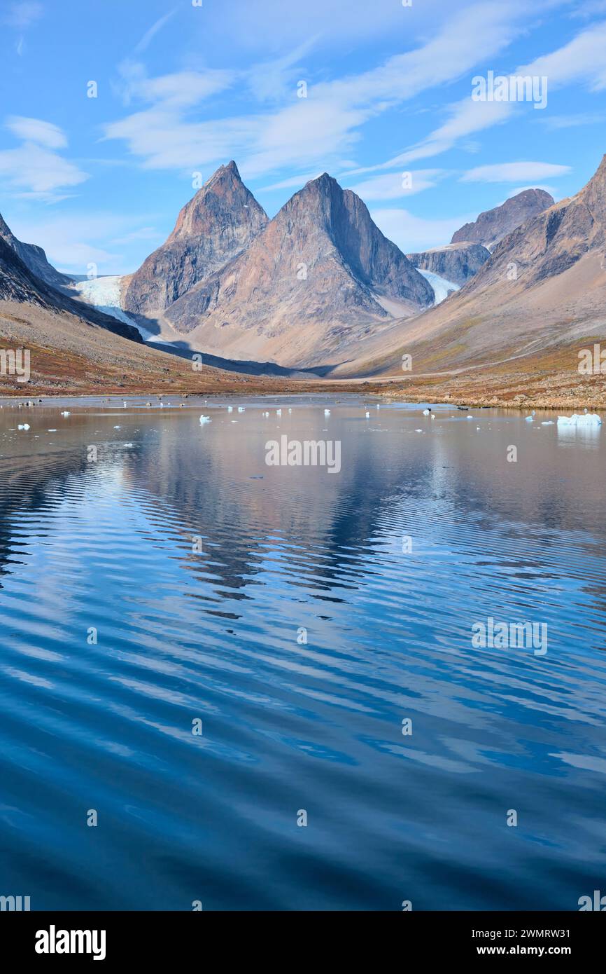 Fast symmetrisch: Zwei Gipfel und zwei Gletscher der Dronning Marie Dal spiegeln sich im sanft gekräuselten Fjord nahe Skoldungen, Ostgrönland Stockfoto