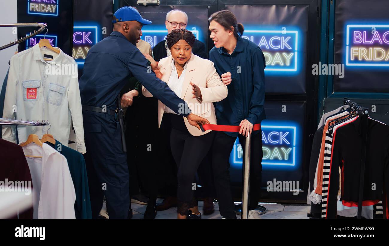 Bekleidungsgeschäft am schwarzen freitag geöffnet, Käufer betreten die Boutique eines Kaufhauses, um von Sonderangeboten zu profitieren. Verschiedene Käufer, die während des saisonalen Verkaufs Rabattkleidung kaufen möchten. Stockfoto