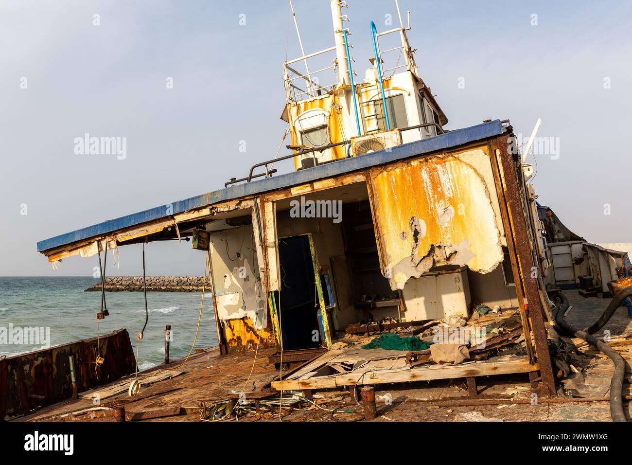 Abgerissenes und rostiges Deck eines Frachtschiffes mit alter Brücke, Mast, Antennen und Maschinen, das am Strand von Al Hamriyah in Umm Al Quwain, Vereinigte Arabische Emirate an Land gespült wurde Stockfoto