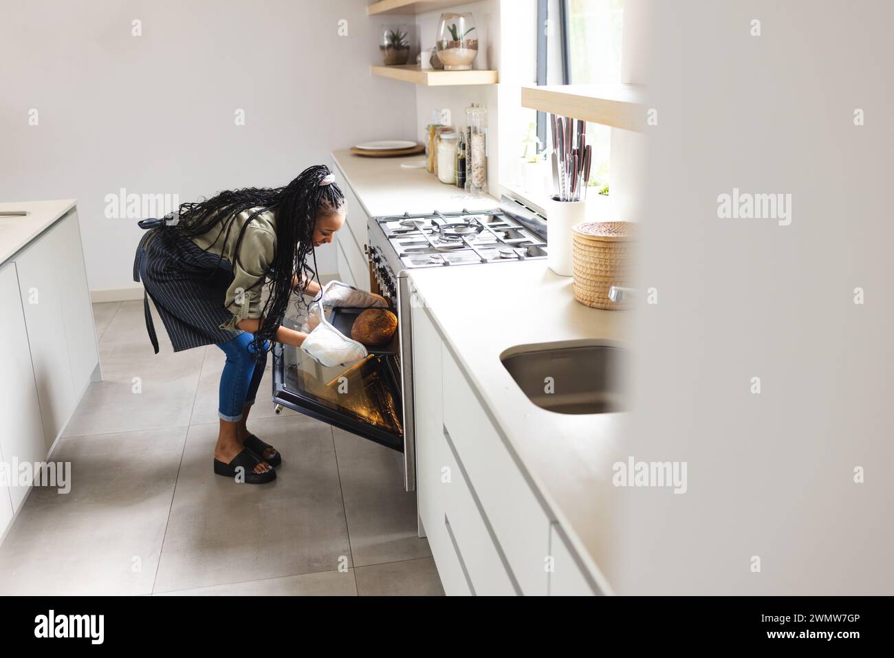 Eine junge Afroamerikanerin überprüft in einem Ofen mit Kopierraum das Essen Stockfoto
