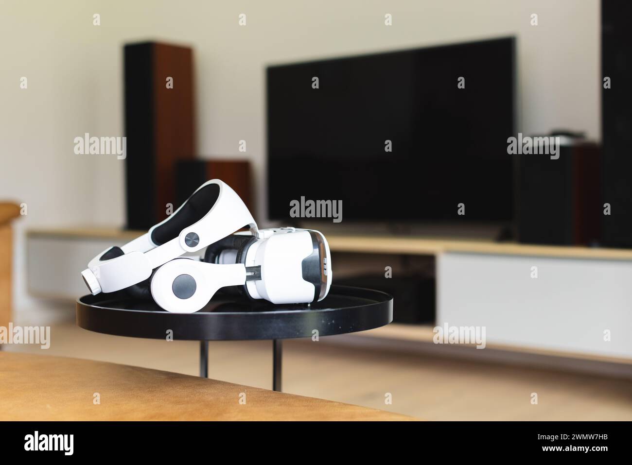 Ein weißes Virtual-Reality-Headset liegt auf einem schwarzen Tisch in einem modernen Wohnzimmer mit Kopierraum auf Stockfoto