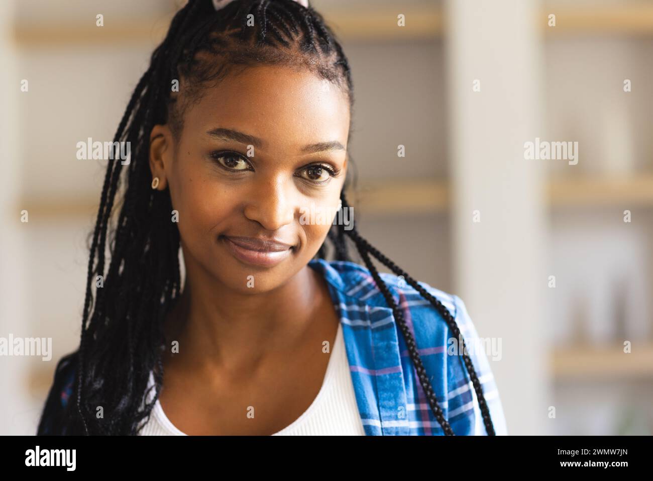 Eine junge Afroamerikanerin mit geflochtenem Haar lächelt sanft in die Kamera Stockfoto
