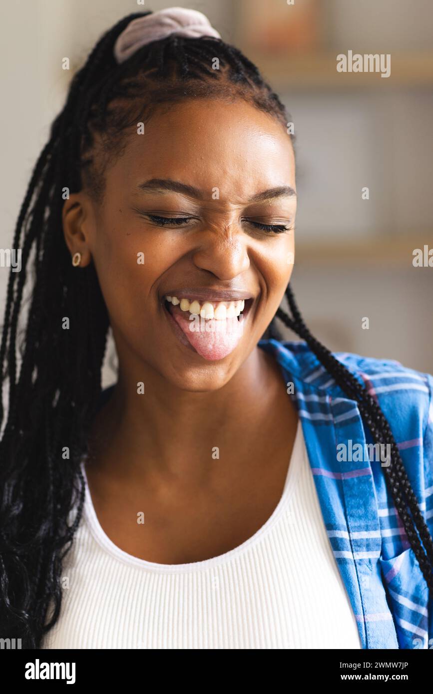 Die junge afroamerikanische Frau lacht fröhlich und streckt ihre Zunge spielerisch aus Stockfoto