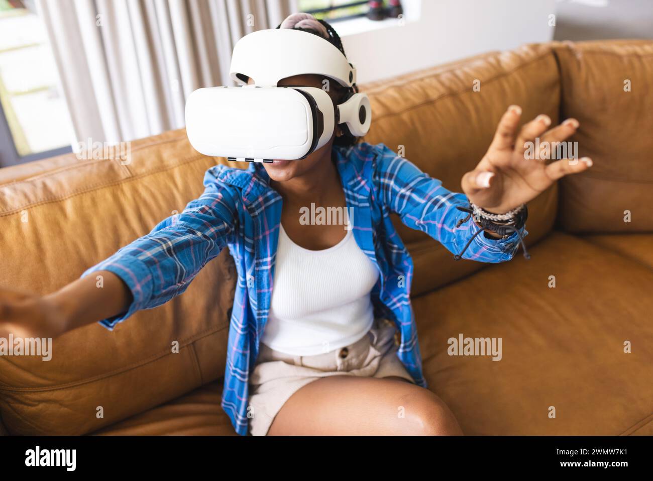 Die junge afroamerikanische Frau erforscht die virtuelle Realität, indem sie mit ihren Händen Gesten macht Stockfoto