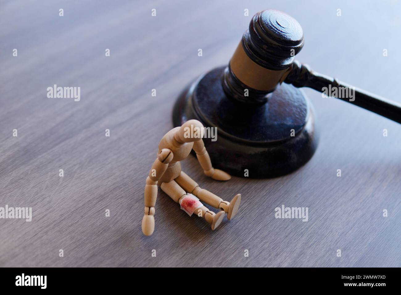 Bandage mit Blutfleck, Holzpuppe und Richter-Hammer. Das Verletzungsgesetz. Stockfoto