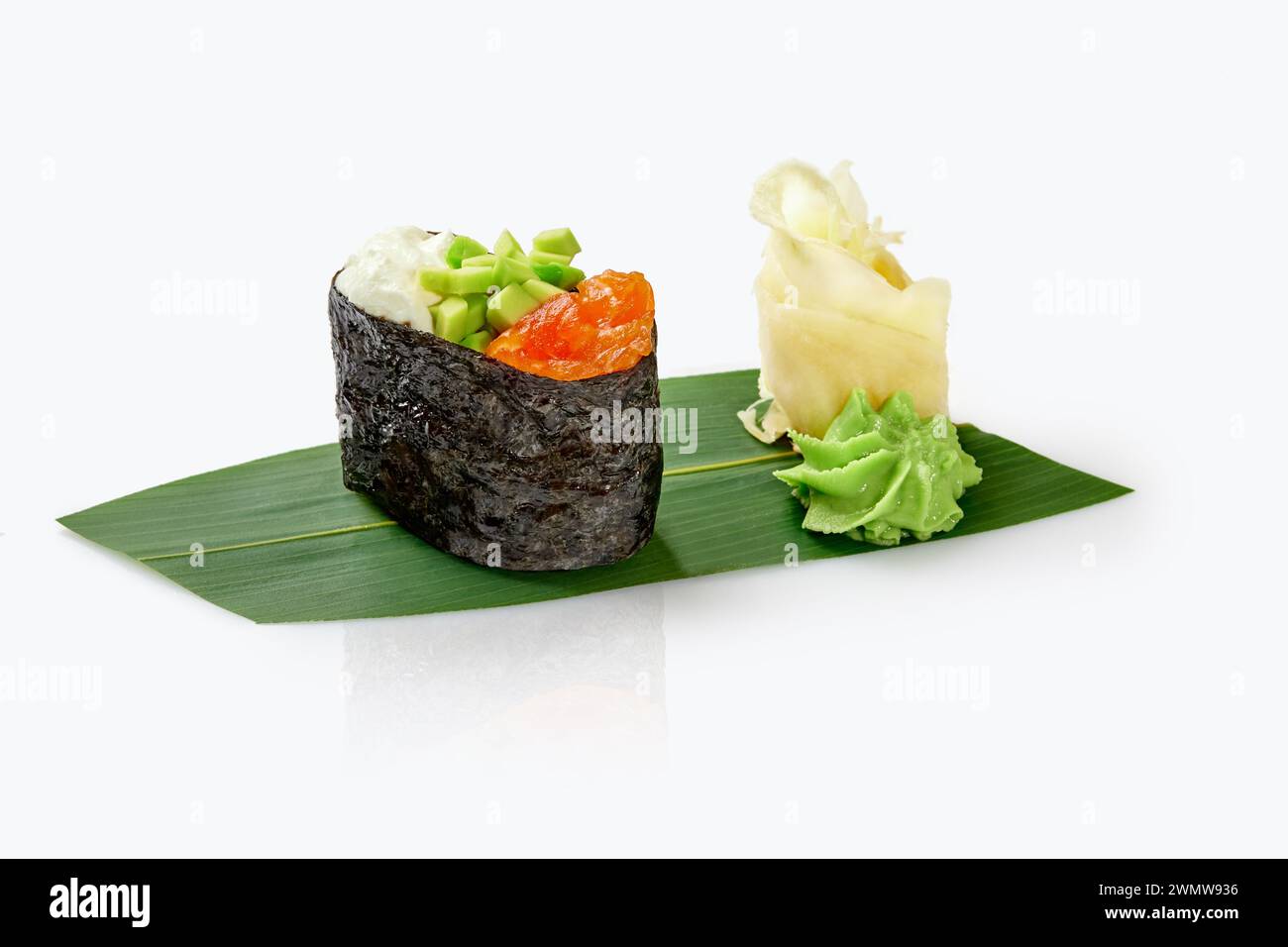 Gunkan Maki Sushi mit Lachsbelag, Avocado und Mayo in Würfel, serviert mit Wasabi und Ingwer auf Bambusblättern isoliert auf weiß. Traditionelles japanisches cu Stockfoto