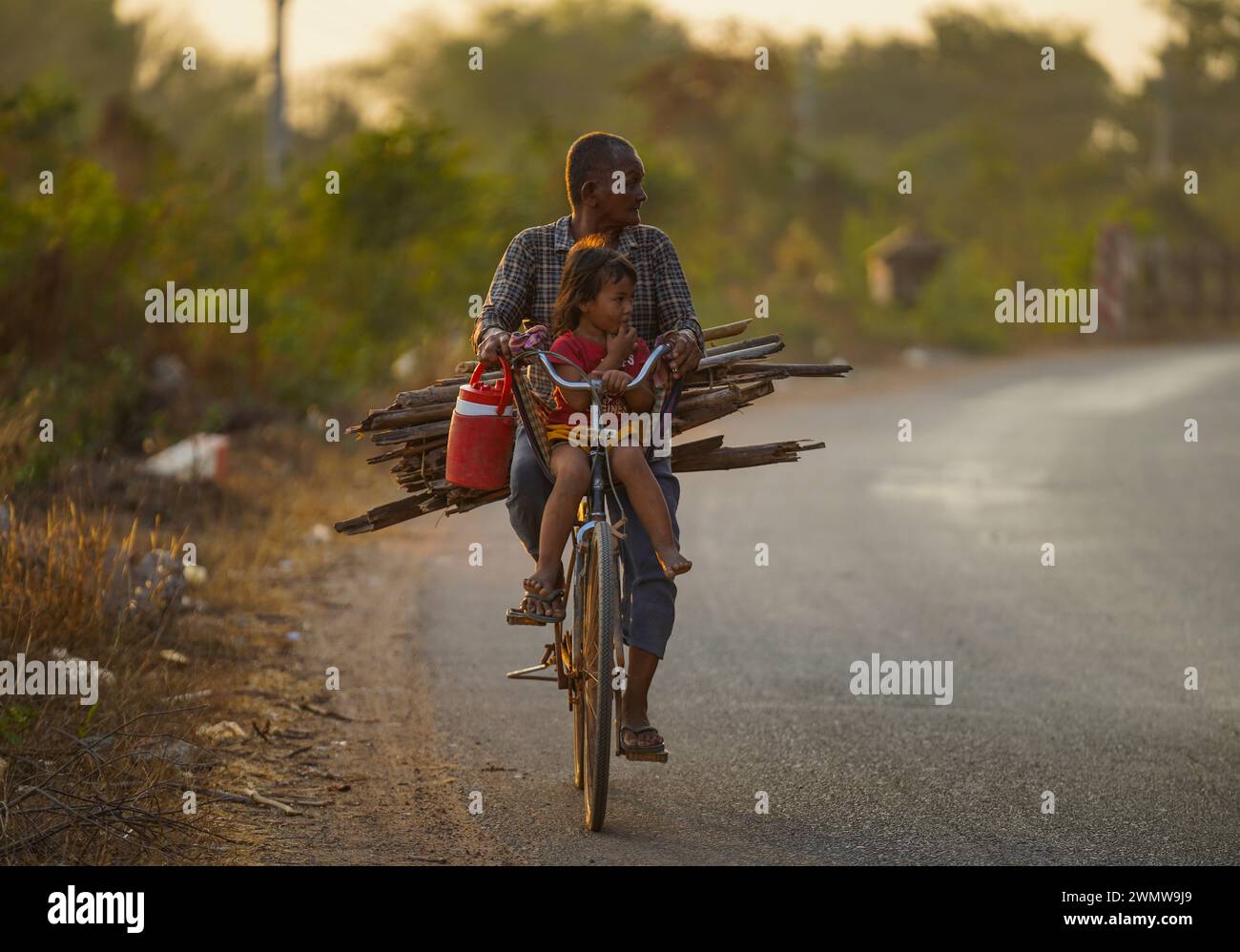 Oma nimmt ihre Enkelin von der Arbeit mit Holz für das Kochen in Skun, Kampong Cham Stockfoto