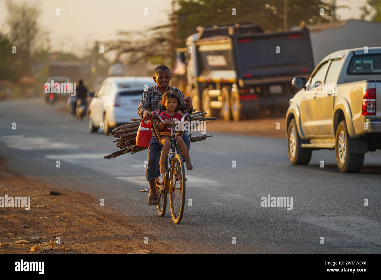 Oma nimmt ihre Enkelin von der Arbeit mit Holz für das Kochen in Skun, Kampong Cham Stockfoto