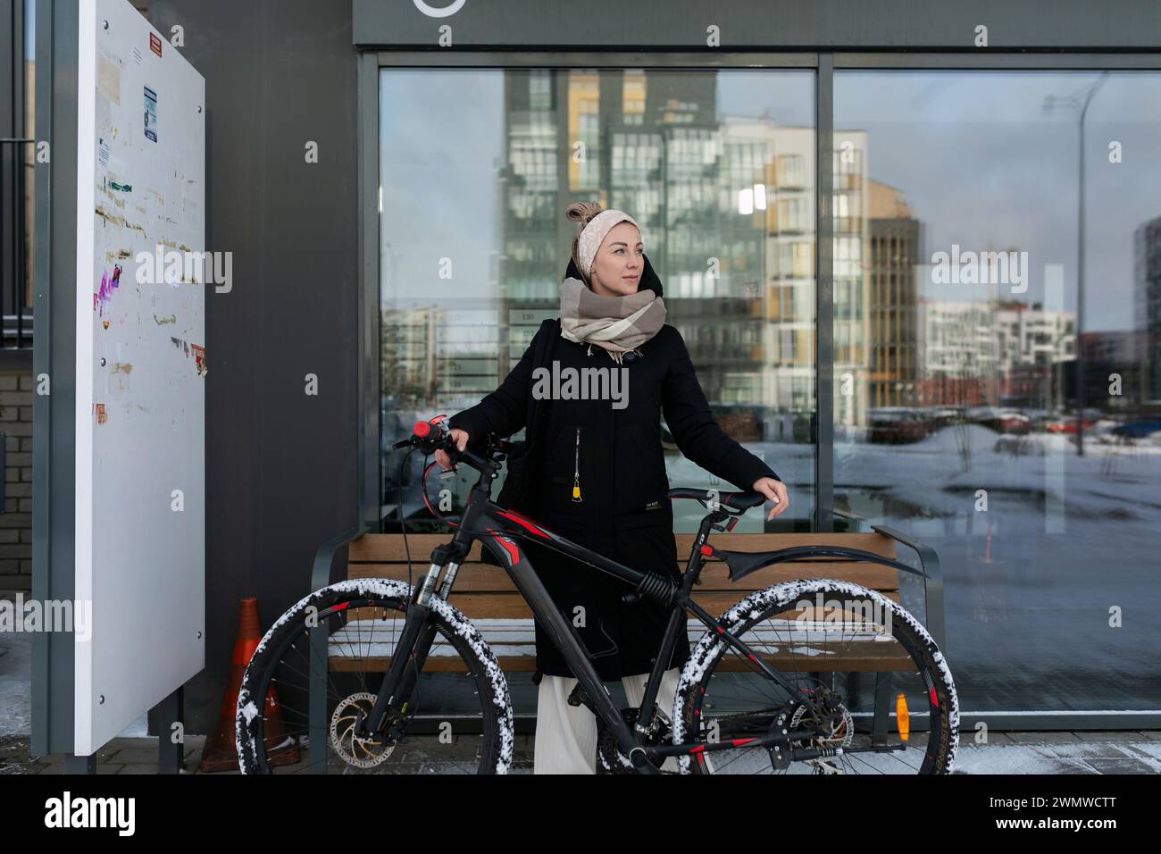 Lächelnde, süße Frau mit blonden Dreadlocks hat sich im Winter ein Fahrrad gemietet Stockfoto