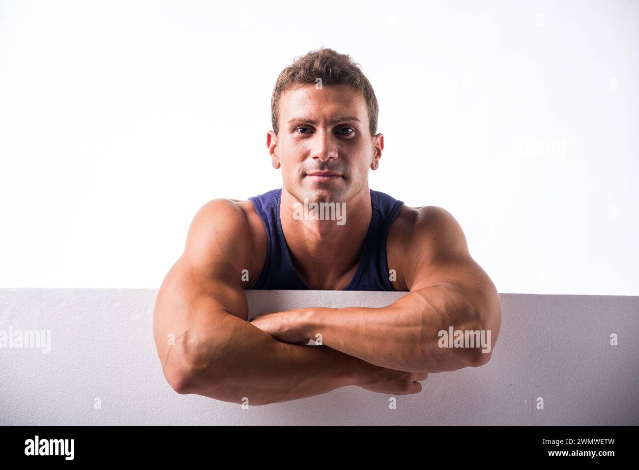 Ein Mann steht in einer Pose mit überkreuzten Armen und blickt direkt in die Kamera. Er wirkt selbstbewusst und selbstbewusst in seiner Haltung. Stockfoto Ein Mann steht in einer Pose mit überkreuzten Armen und blickt direkt in die Kamera. Er wirkt selbstbewusst und selbstbewusst in seiner Haltung. Stockfoto