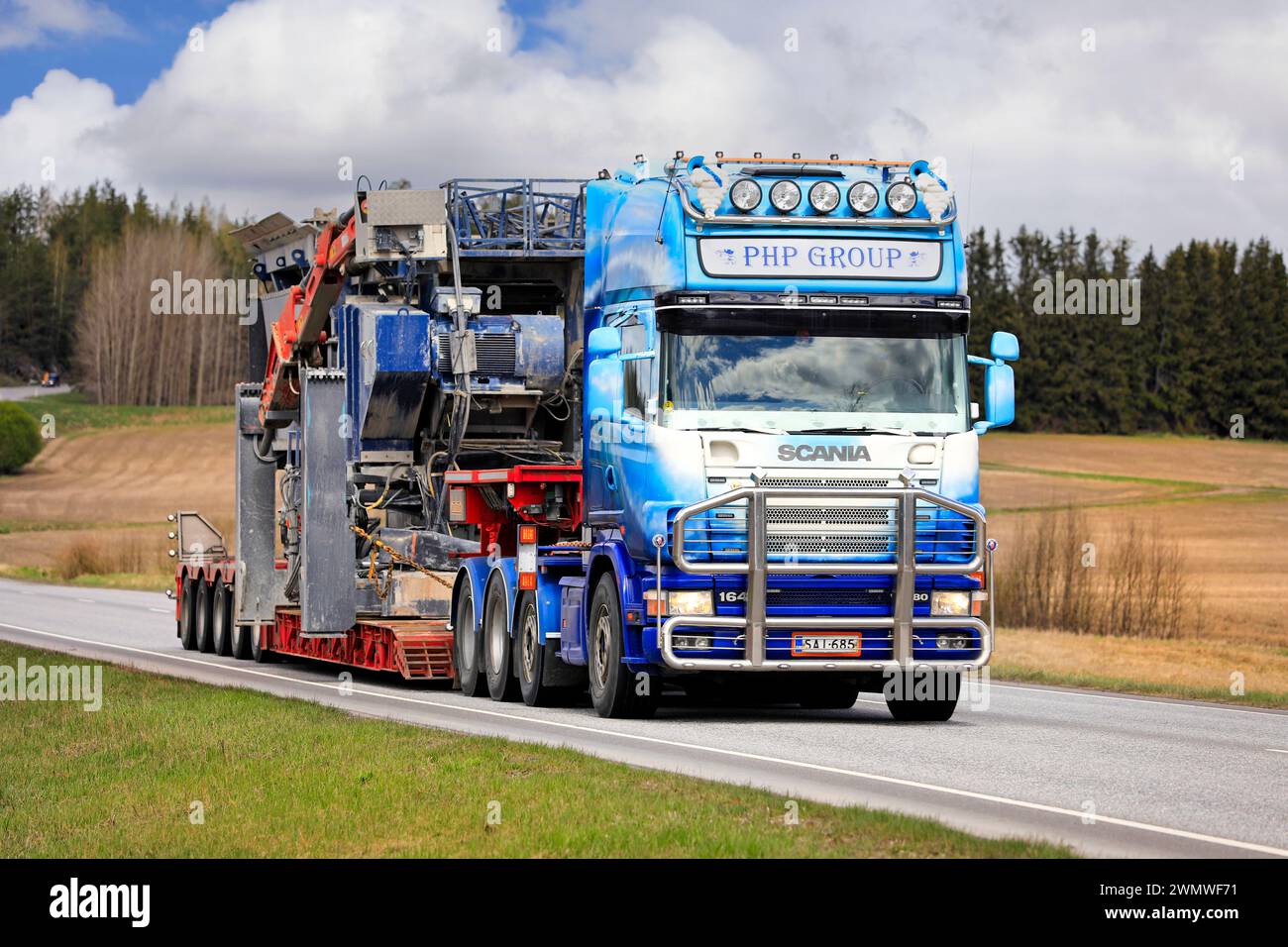 Der maßgeschneiderte Scania 164 Lkw-Auflieger PHP Group Oy transportiert Brechmaschinen als Übergröße entlang der Autobahn 52. Salo, Finnland. Mai 2022. Stockfoto