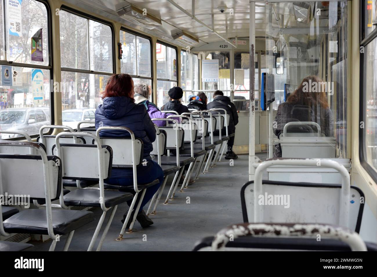 Die Passagiere pendeln in der alten Straßenbahn ČKD T6B5 mit einem langweiligen, altmodischen, grauen Innenraum. Stockfoto