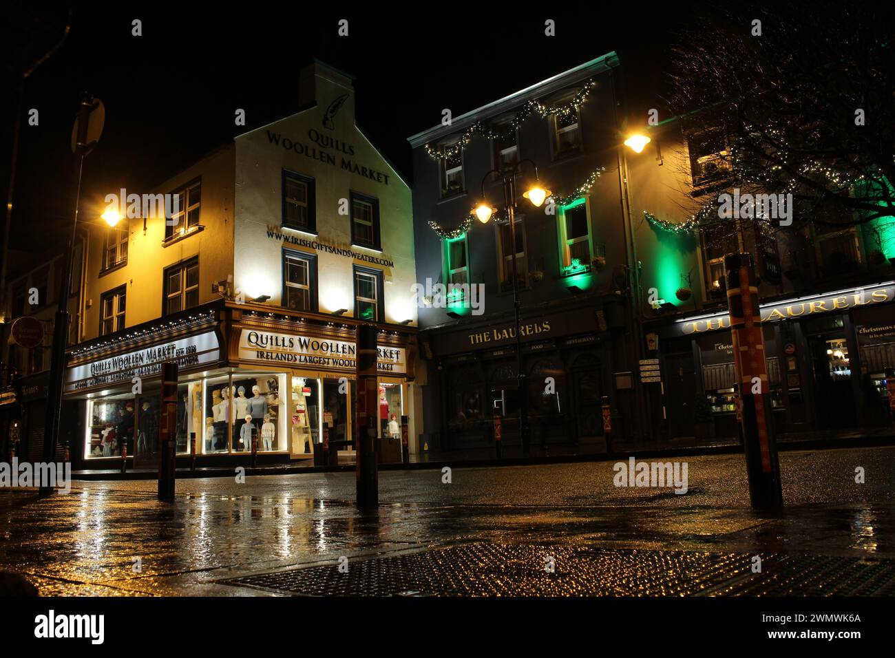 Niedriger Blick auf die Killarney High Street in der Nacht im Winter nach dem Regen im County Kerry Irland. Nächtlicher Blick auf die kleine Stadt Stockfoto