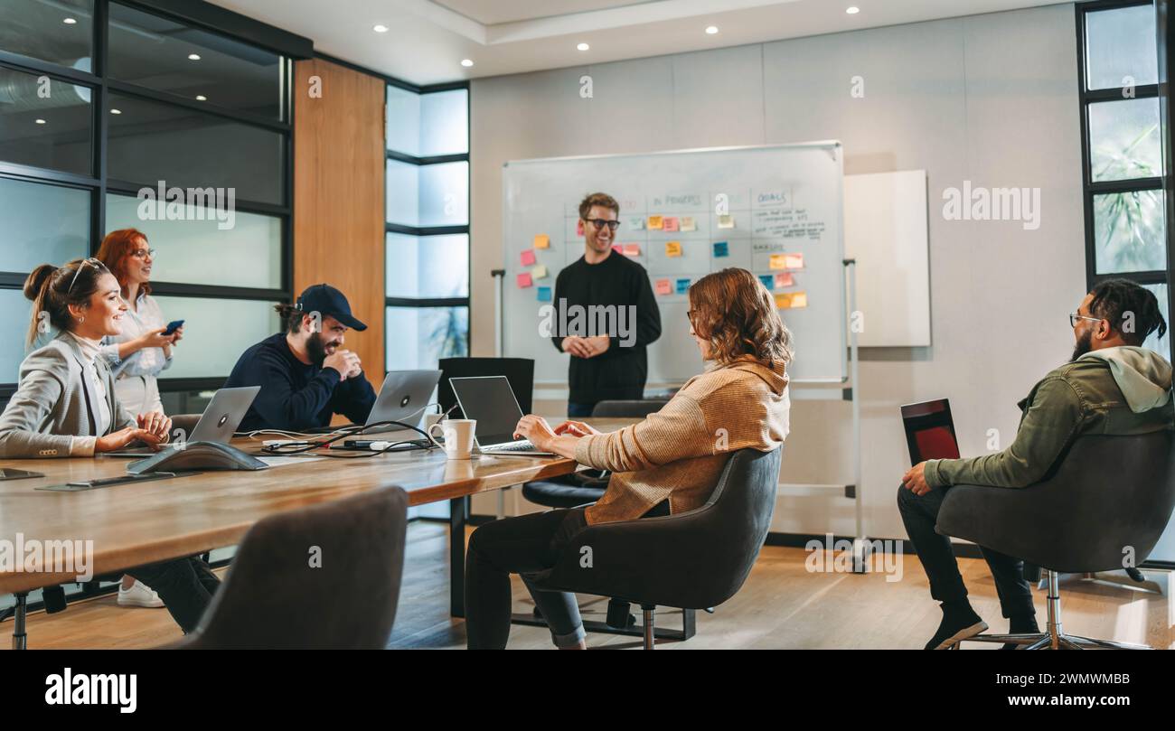 Experten aus verschiedenen Gruppen arbeiten in einem Konferenzraum zusammen und nehmen an einem lebhaften Brainstorming Teil. Sie diskutieren Ideen, zeigen Teamarbeit und c Stockfoto