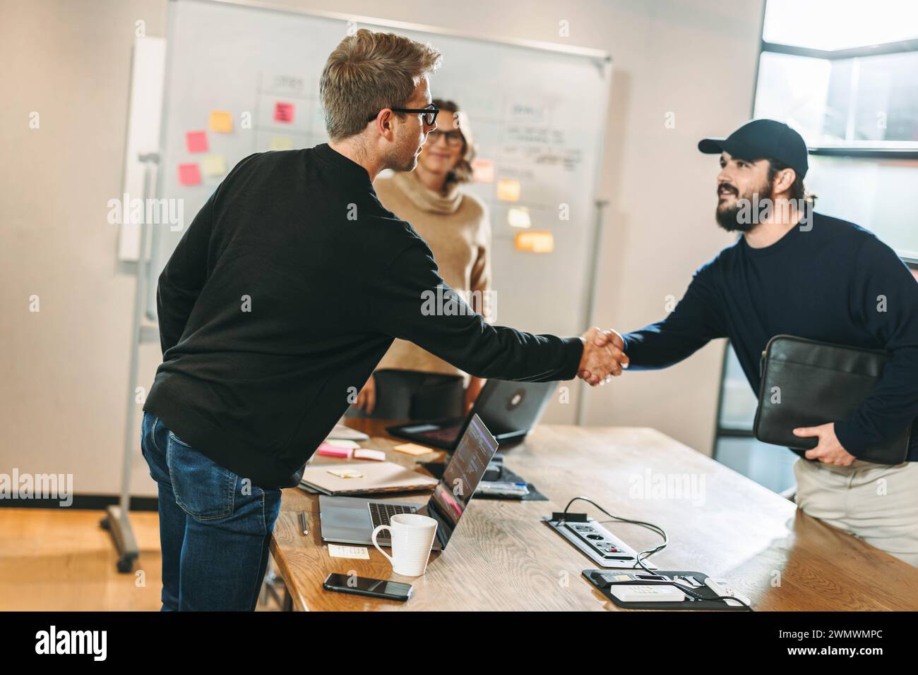 Zwei Software-Entwickler schütteln die Hand, um einen Deal für ein Softwareentwicklungsprojekt zu festigen. Geschäftsleute, die an einem produktiven Meeting teilnehmen Stockfoto