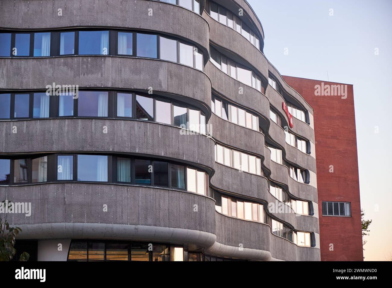 Das moderne Gebäude verfügt über geschwungene Fassaden und Spiegelglas, das zeitgenössische Eleganz und architektonische Innovation ausstrahlt Stockfoto