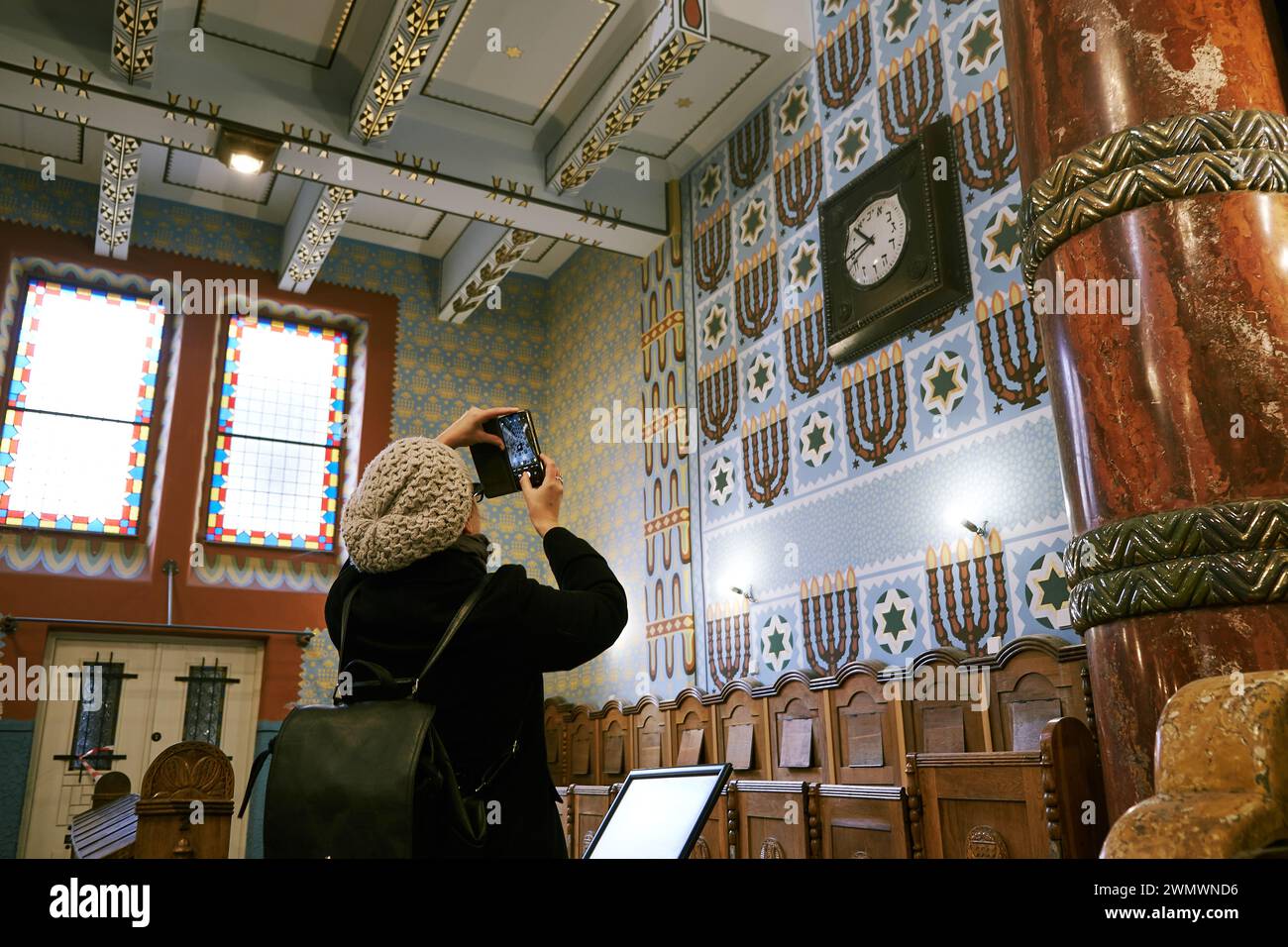 Eine Frau fängt mit ihrem Smartphone einen Moment in der Synagoge der Kazinczy Street in Budapest ein und verbindet moderne Technologie mit historischer Bedeutung. Stockfoto