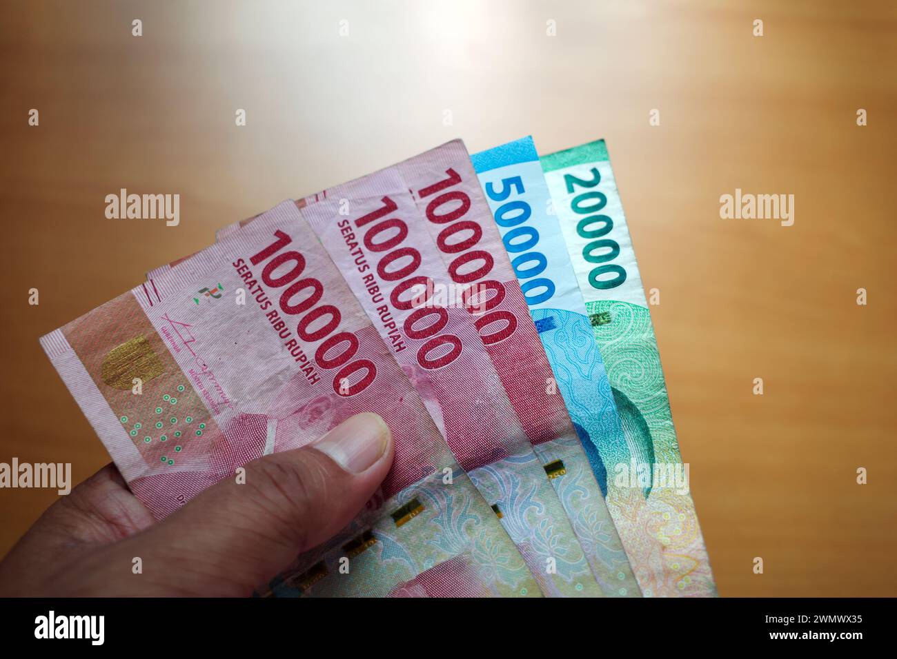 Ein asiatischer Mann hält indonesisches Geld, in oberster Konzentration. Sparen und Geben des Konzepts. Stockfoto