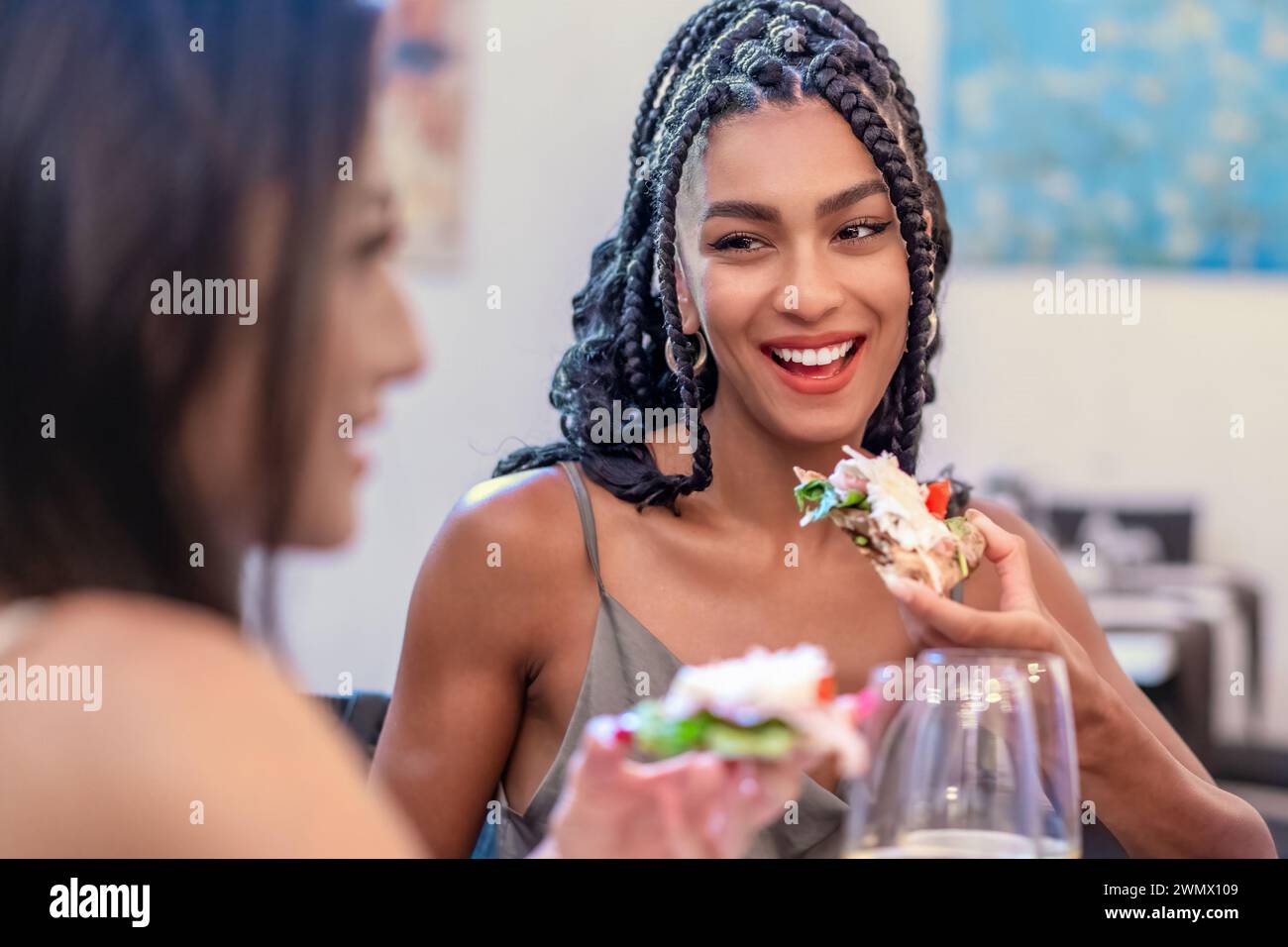 Lächelnde junge Frau, die ein frisches, köstliches Essen genießt - zwangloses Essen in urbaner Umgebung - Gourmet-Erlebnis mit Freunden. Stockfoto