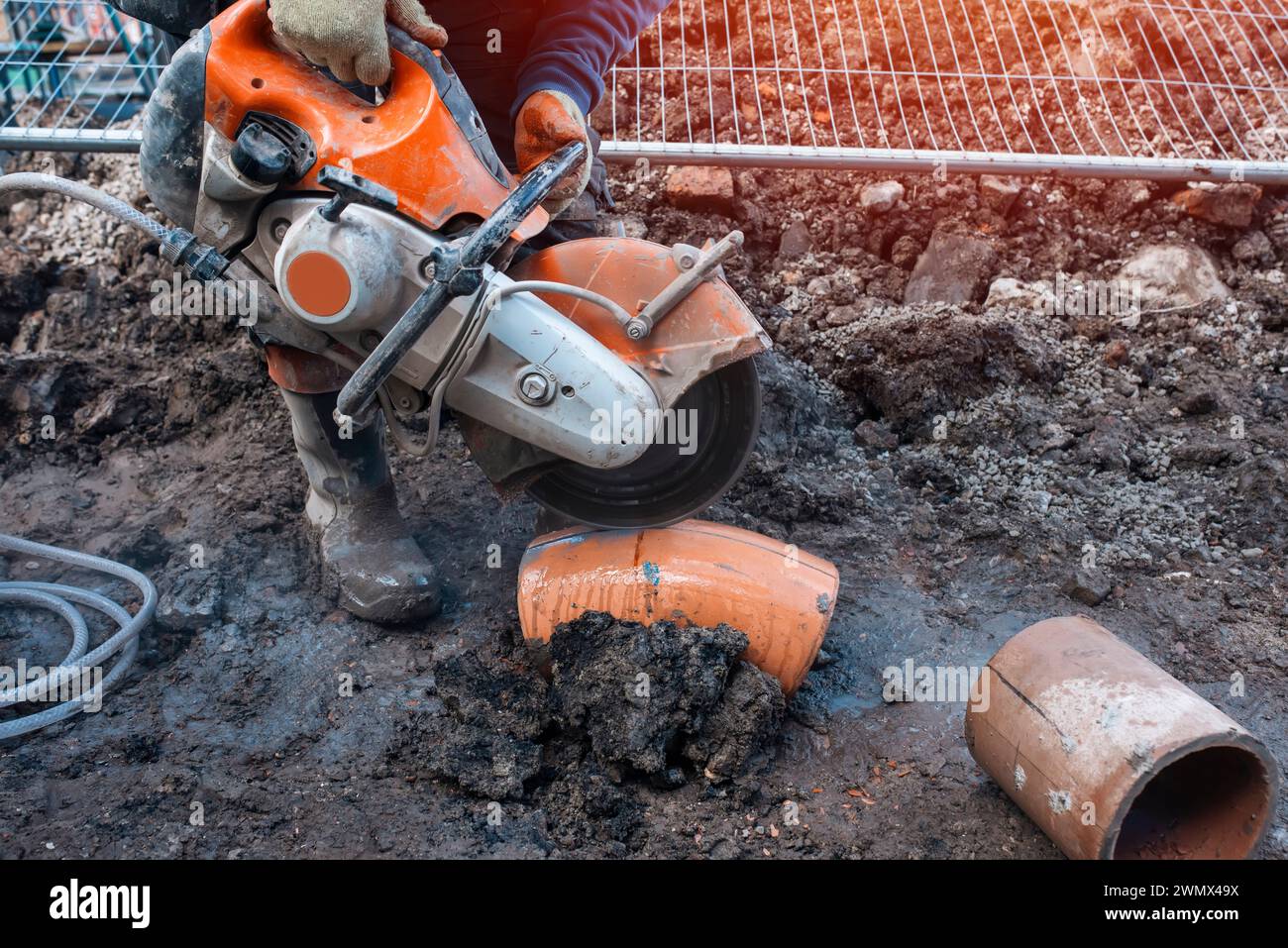 Baumeister schneidendes Tonrohr mit Benzin-Betonsäge und Diamanttrennscheibe Stockfoto