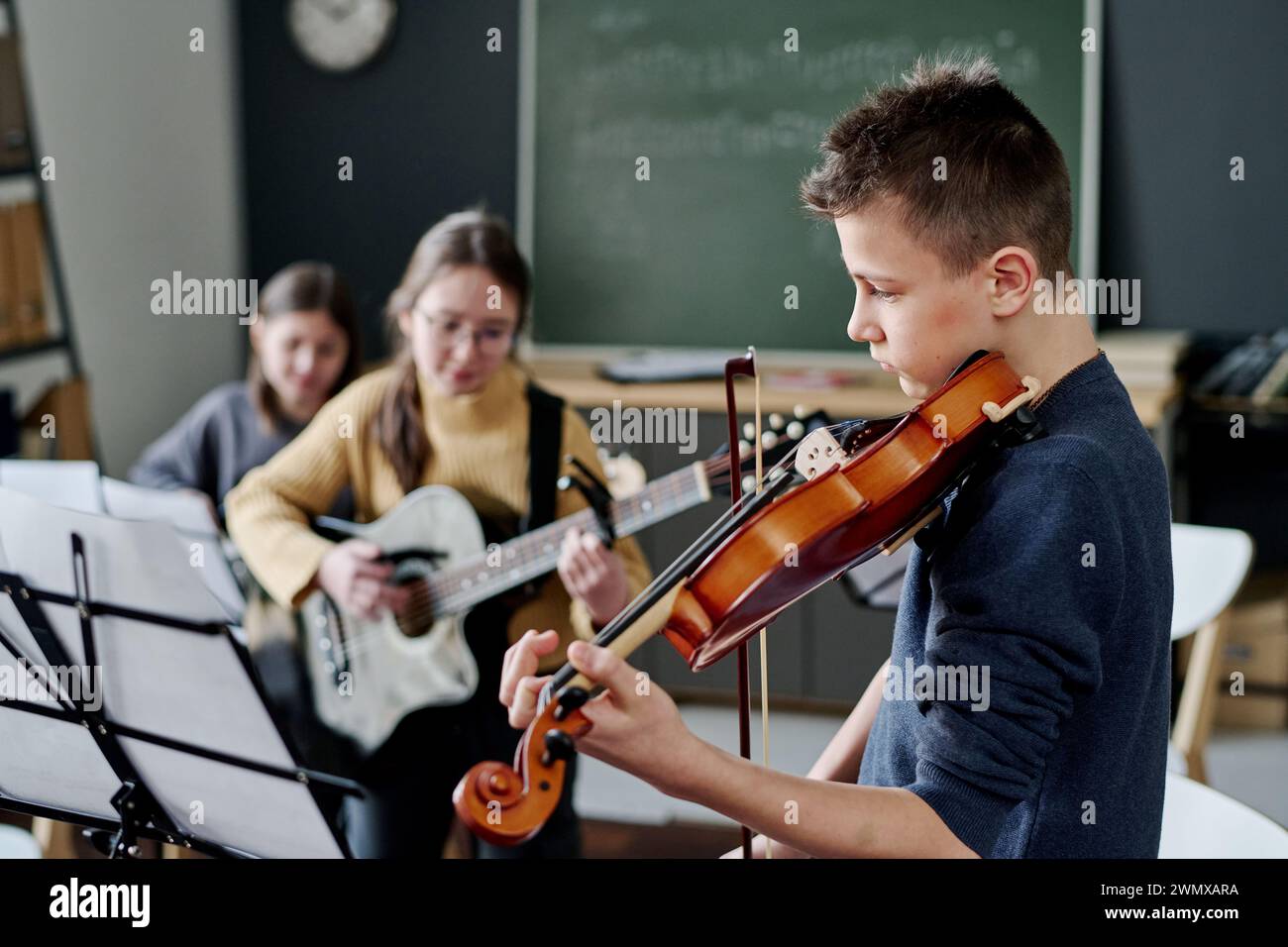 Selektive Fokusaufnahme einer modernen Mittelschulband, die Musik im Klassenzimmer, im Kopierraum übt Stockfoto