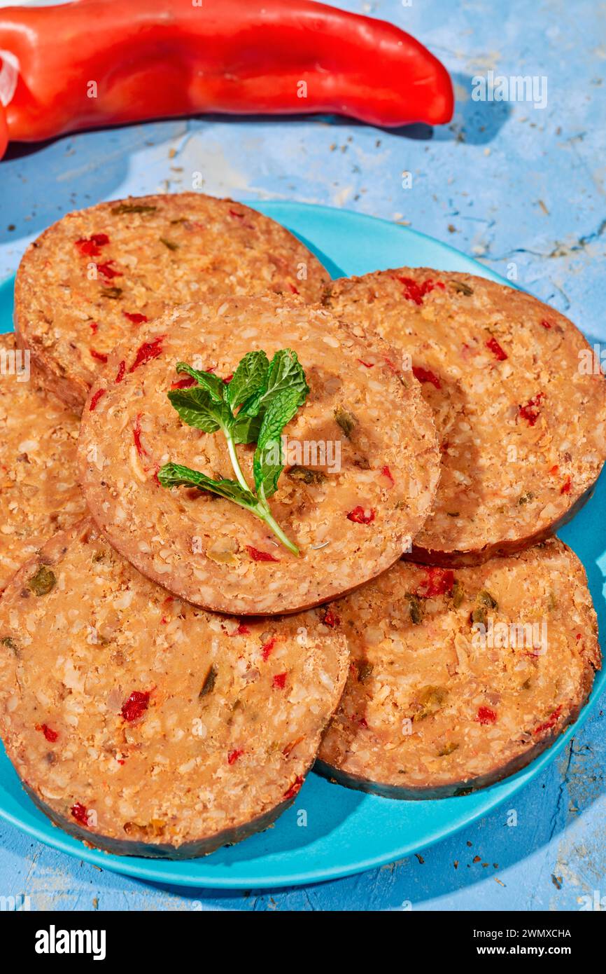 Einige Scheiben einer veganen Brötchen, die mit Pilzen und Pfeffer zubereitet werden, auf einer blauen Platte, auf einer rustikalen strukturierten Oberfläche Stockfoto