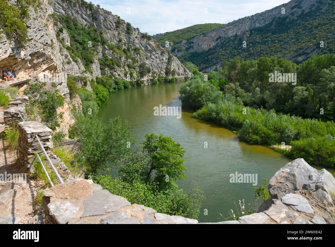 Ein idyllischer Pfad entlang eines ruhigen Flusses mit Blick auf steile Felswände Stockfoto