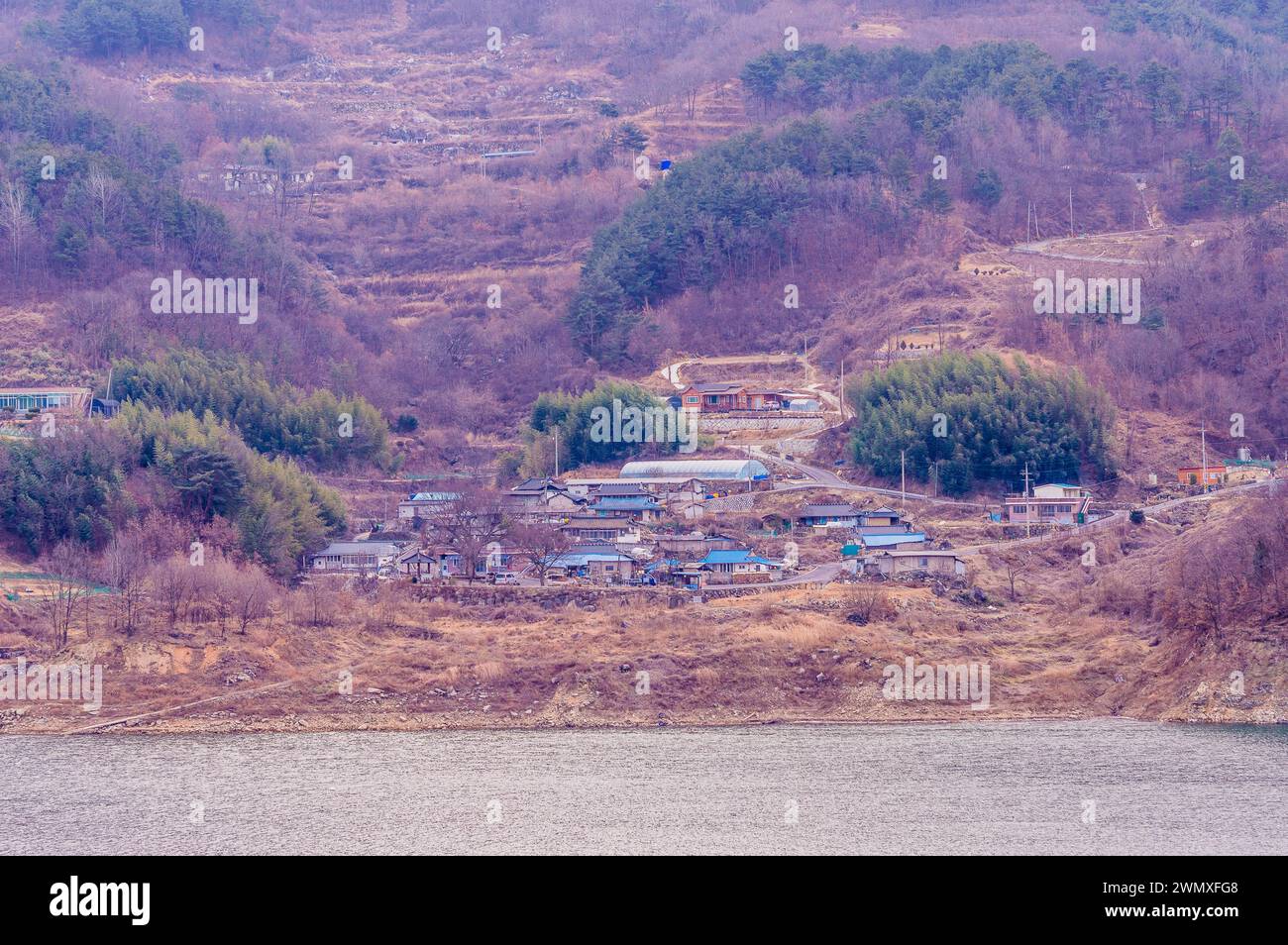 Abgelegenes Dorf auf der anderen Seite des Wassers, eingebettet zwischen Bäumen in einer ruhigen Umgebung, in Südkorea Stockfoto