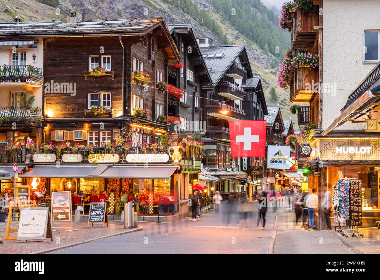 ZERMATT, SCHWEIZ - 14. OKTOBER 2023: Die historische Bahnhofstraße in der Abenddämmerung. Stockfoto