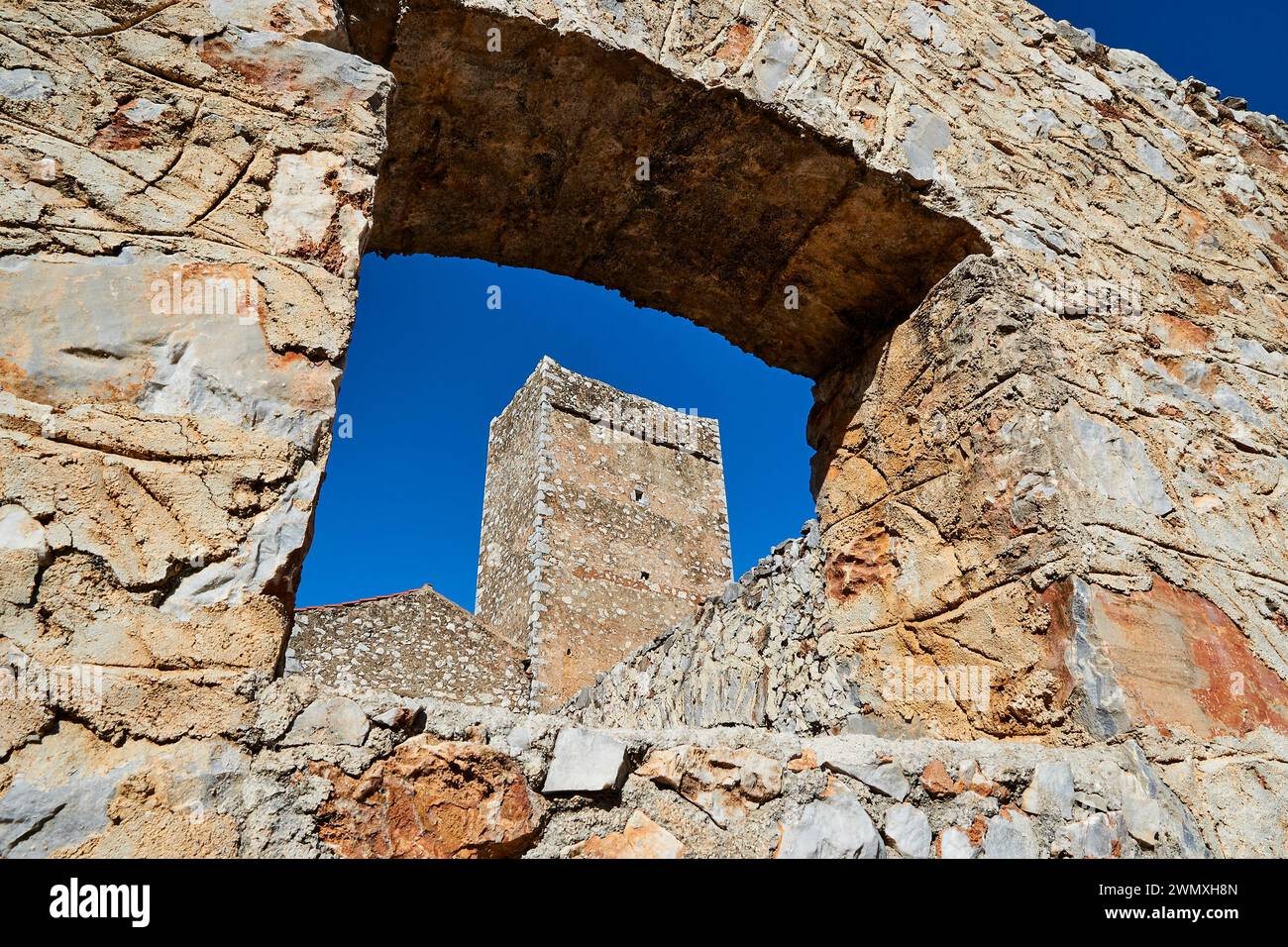 Blick durch einen Ruinenbogen zu einem klaren Himmel und anderen Steinstrukturen, Flomochori, Wohntürme Dorf, Mani Halbinsel, Peloponnes, Griechenland Stockfoto