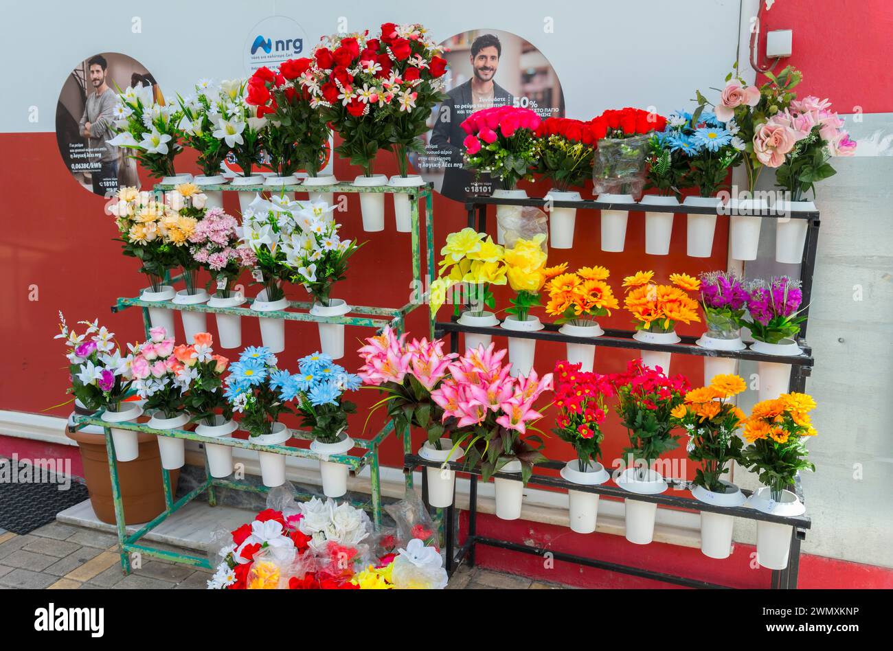 Ein farbenfroher Blumenstand mit verschiedenen künstlichen Blumen vor einem Geschäft, Gastouni, Elis, Peloponnes, Griechenland Stockfoto