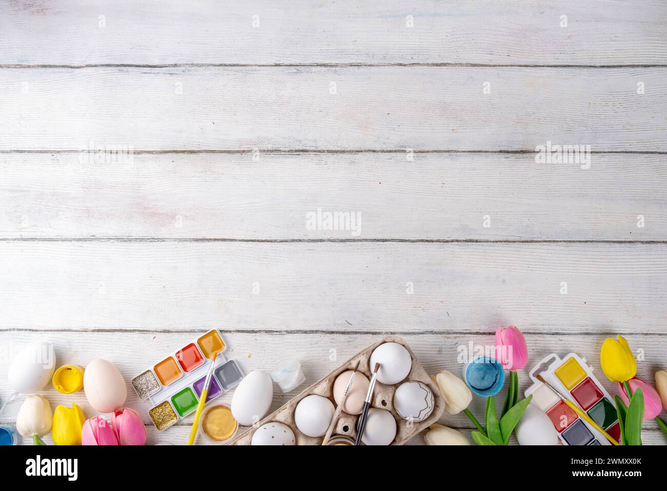 Familientraditionen, Vorbereitung auf das Osterkonzept. Frühlingsblumen Tulpen, dekorative Ostereier mit Farben, Pinsel, Zubehör zum Zeichnen und Pai Stockfoto