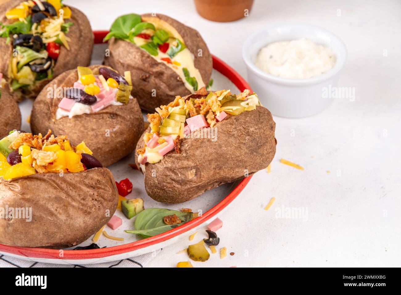 Hausgemachte Kartoffel mit verschiedenen Belägen - Fleisch, Würstchen, Gemüse, Käse, mit weißer Käsesauce, Kopierraum Stockfoto