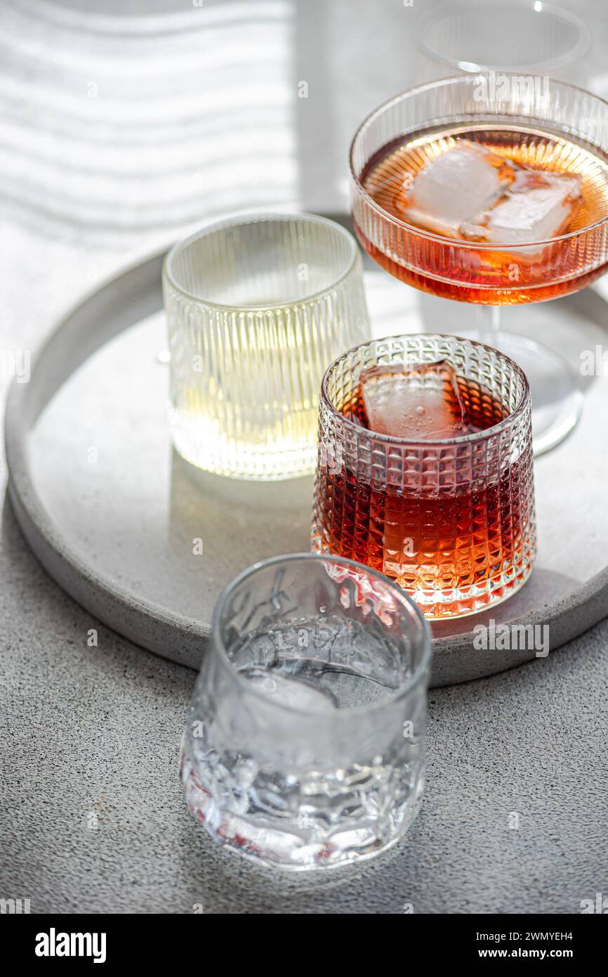 Eine Auswahl an alkoholischen Getränken auf einem runden Tablett, jedes Glas präsentiert einzigartig ein anderes Getränk, einschließlich Cognac mit Zimt, Limoncello mit Stockfoto