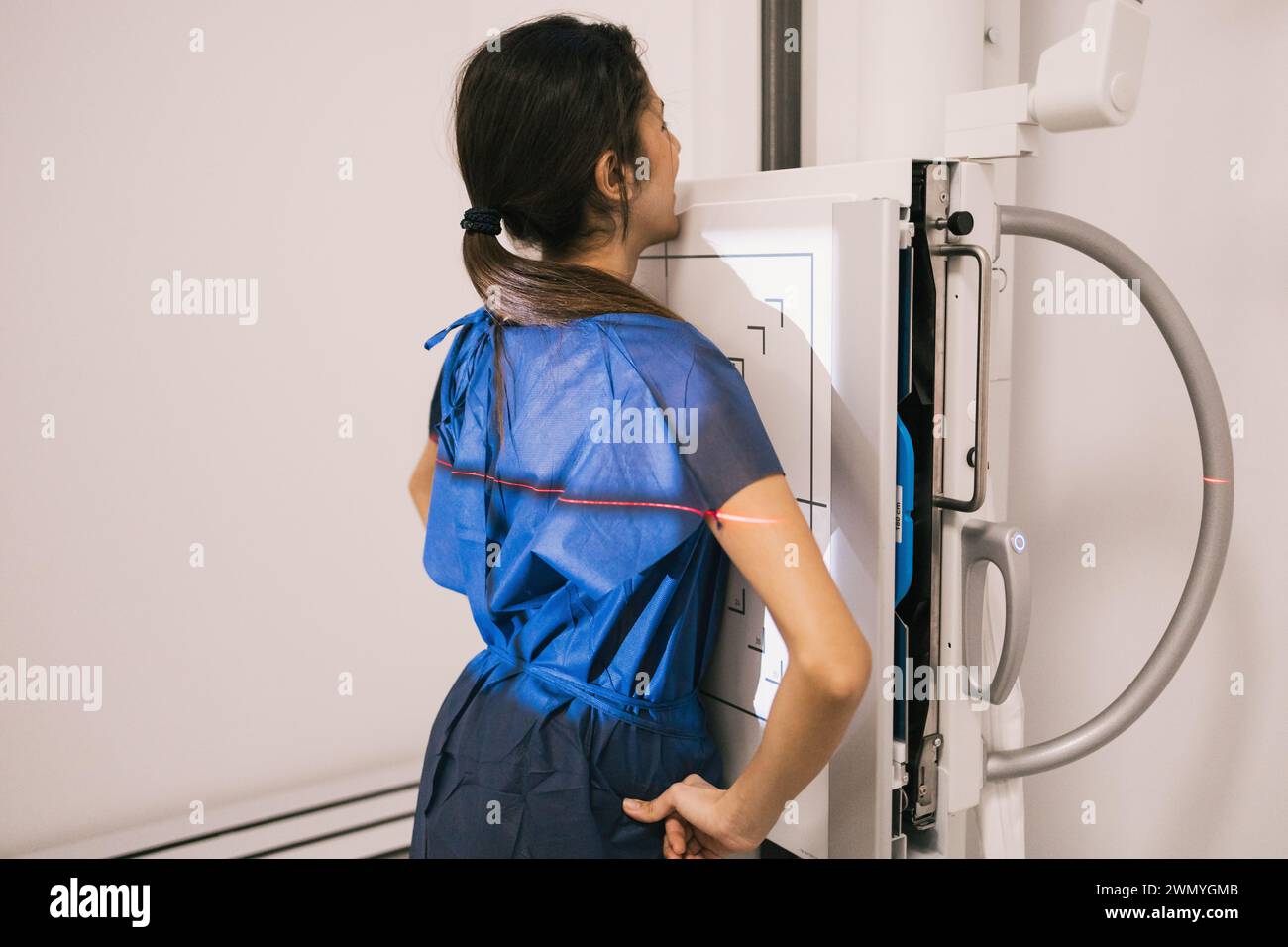 Ein Medizintechniker in blauen Peelings konzentriert sich auf den Betrieb fortschrittlicher diagnostischer Bildgebungsmaschinen in einer klinischen Umgebung. Stockfoto