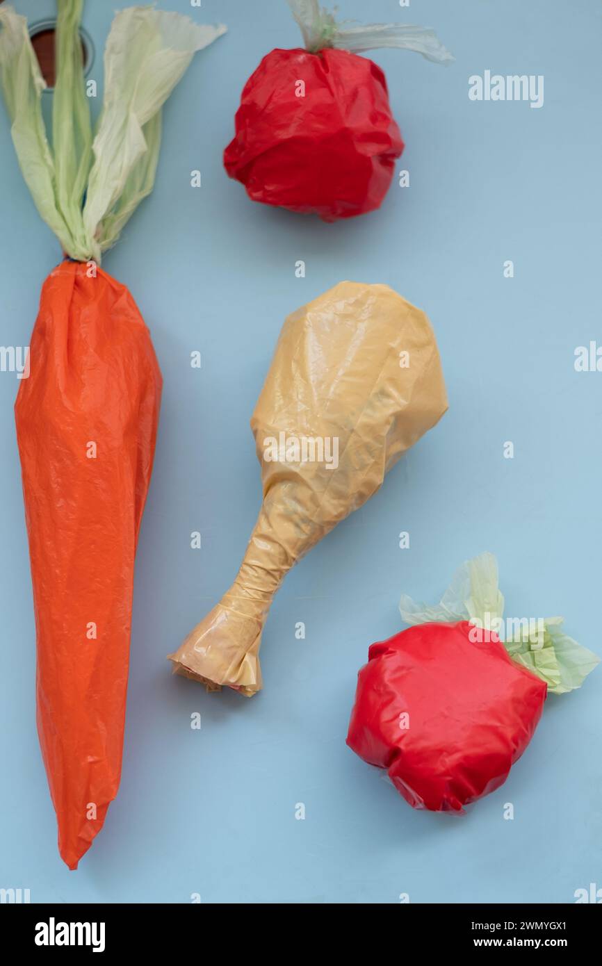 Konzeptionelle Kunstwerke, die aus Plastiktüten geformte Lebensmittel auf blauem Hintergrund zeigen. Stockfoto