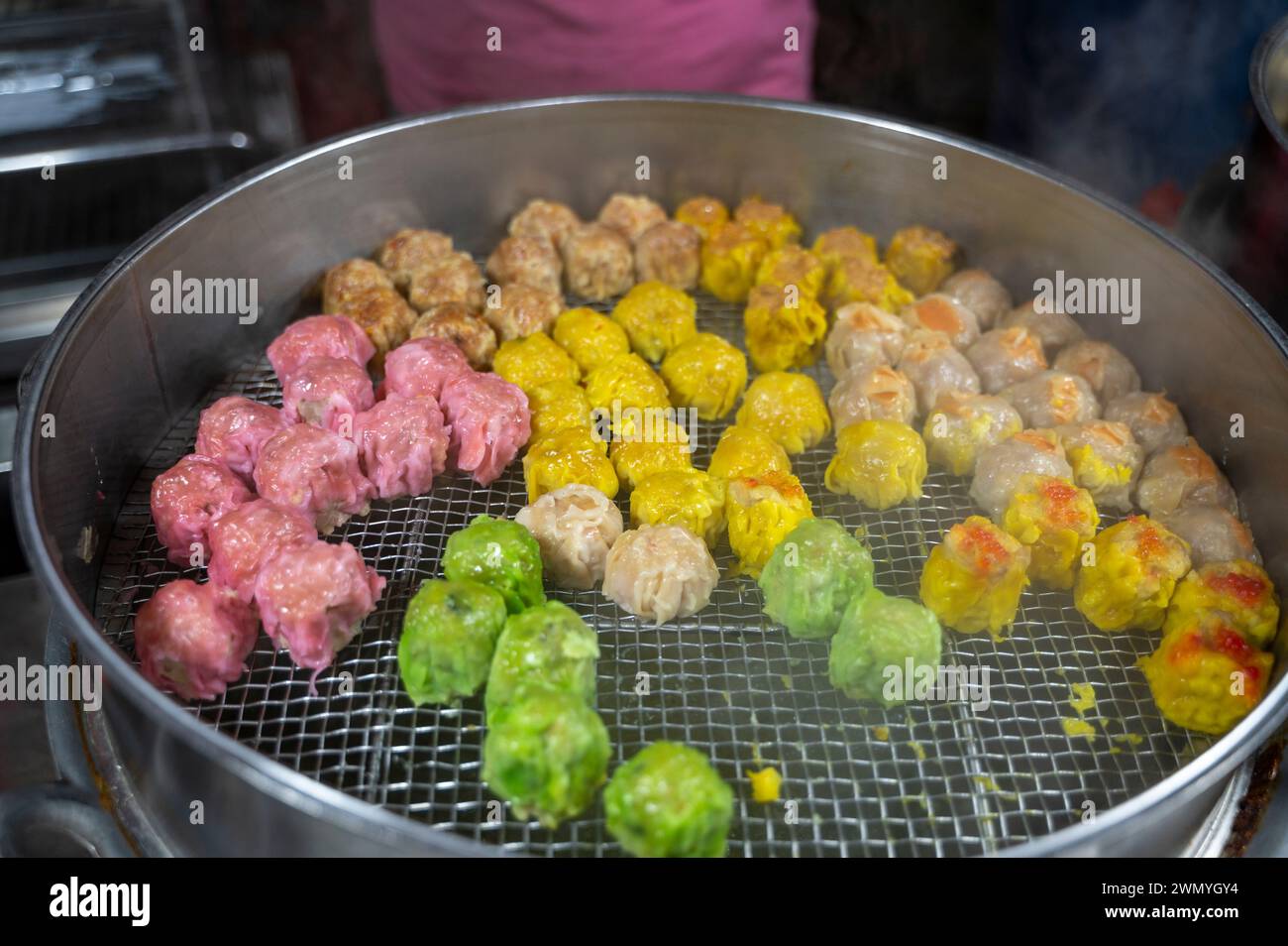 Gedämpfte mehrfarbige Teigtaschen werden auf einem Street Food Markt in Malaysia präsentiert, während der Dampf beim Kochen steigt. Stockfoto