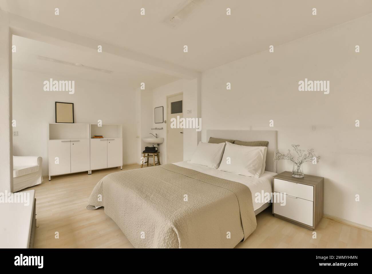 Ein weißes Schlafzimmer mit einem großen Bett und weißen Möbeln Stockfoto