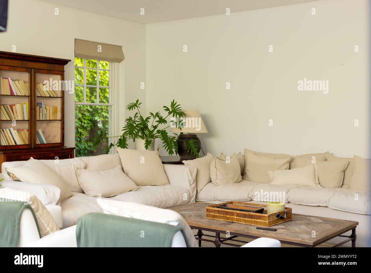 Ein gemütliches Wohnzimmer verfügt über ein weiches beigefarbenes Sofa und einen hölzernen Couchtisch Stockfoto