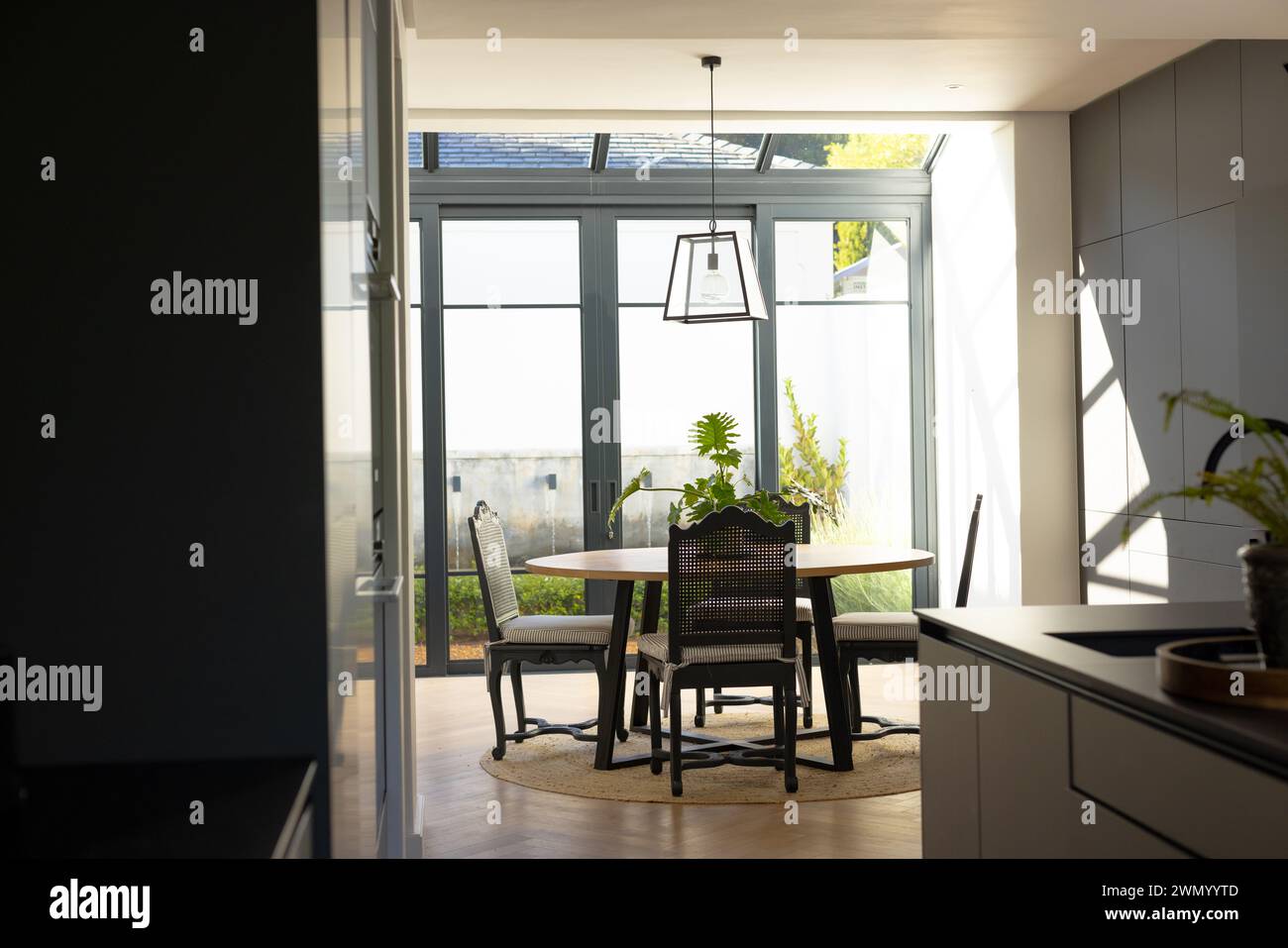 Der moderne Essbereich ist in Tageslicht getaucht und verfügt über einen runden Tisch und schwarze Stühle Stockfoto