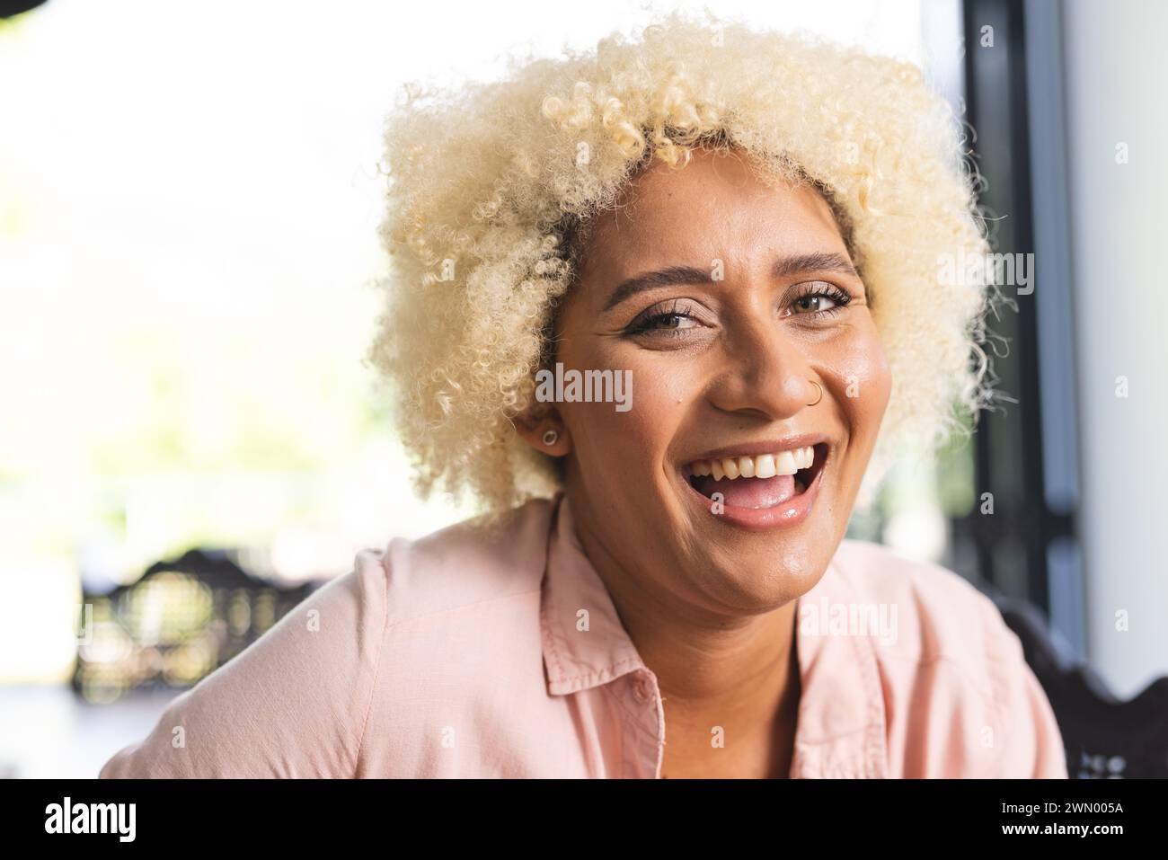 Die junge Frau mit lockigen blonden Haaren lacht freudig Stockfoto